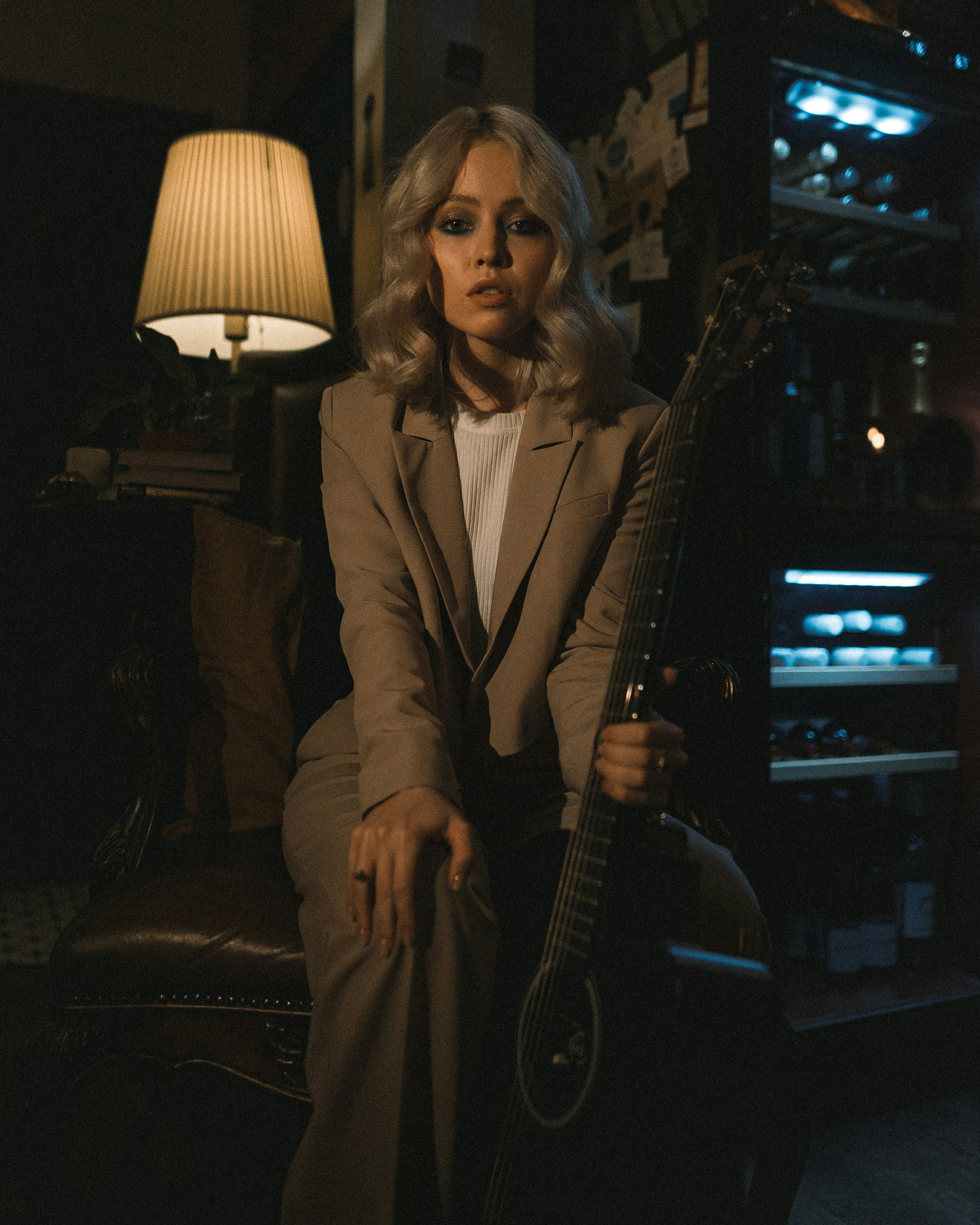 woman in gray coat holding brown acoustic guitar